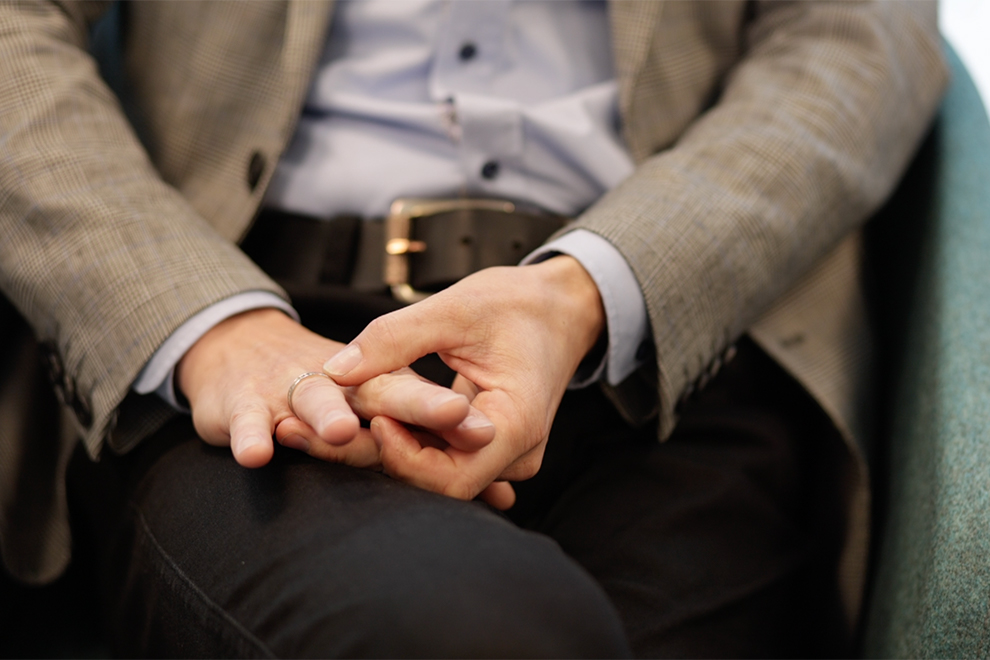 Två händer i en persons knä. Ena handen petar på en ring på andra handen.