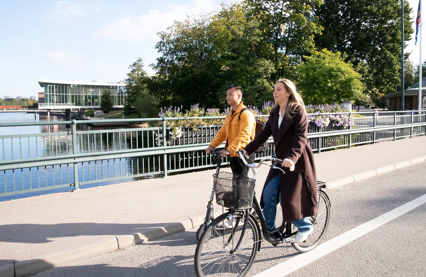 En kvinna och en man cyklar på en bro.. Bild